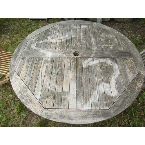 1157 - A weathered circular folding teak garden table with slatted panelled top, 120cm diameter together  w... 