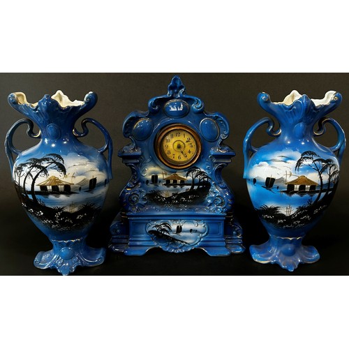 9 - A late 19th/early 20th century ceramic clock garniture comprising mantle clock within a rococo style... 