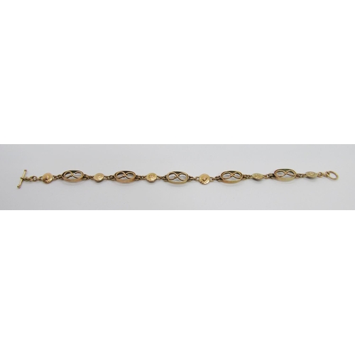 299 - Arts & Crafts yellow metal bracelet with fancy infinity and disc shaped links, 19.5cm L approx, 7.4g