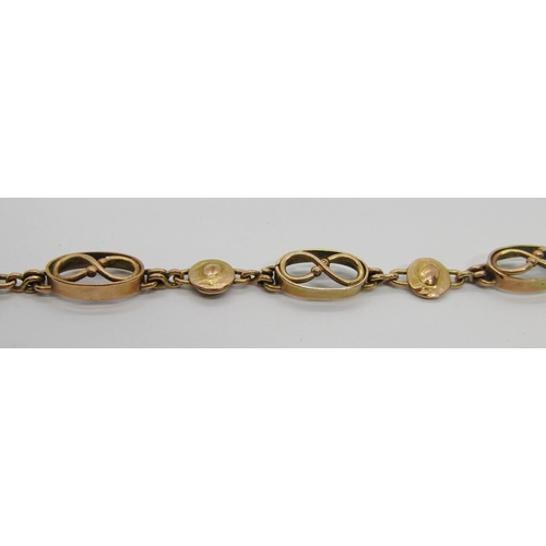 299 - Arts & Crafts yellow metal bracelet with fancy infinity and disc shaped links, 19.5cm L approx, 7.4g