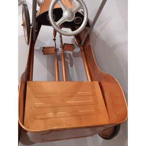 911 - A child's pedal car in good working order with copper coloured finish. Length 83cm