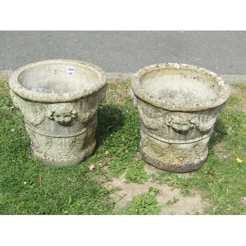 1255 - A pair of weathered cast composition stone planters with classical repeating cherub mask, swag and f... 