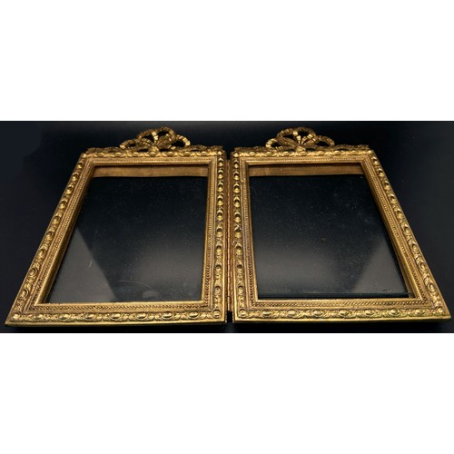 392 - An Edwardian cast brass two panel photograph frame with repeating geometric boarder beneath a ribbon... 