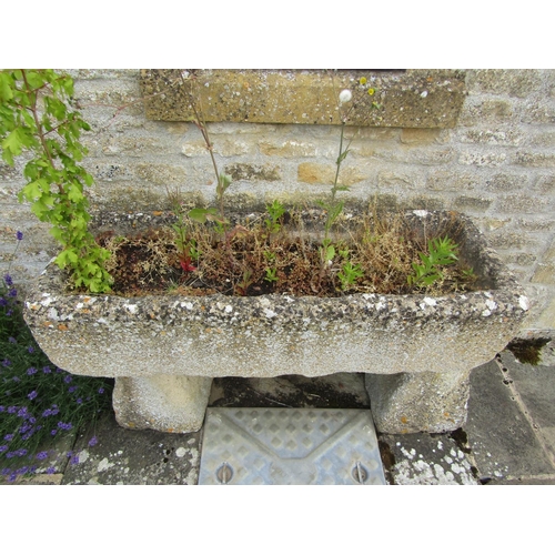 1043 - A weathered composition stone planter / trough of rectangular form raised on an associated pair of t... 