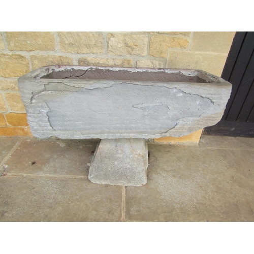 1051 - A roughly hewn weathered natural stone planter / trough of rectangular form raised on an associated ... 