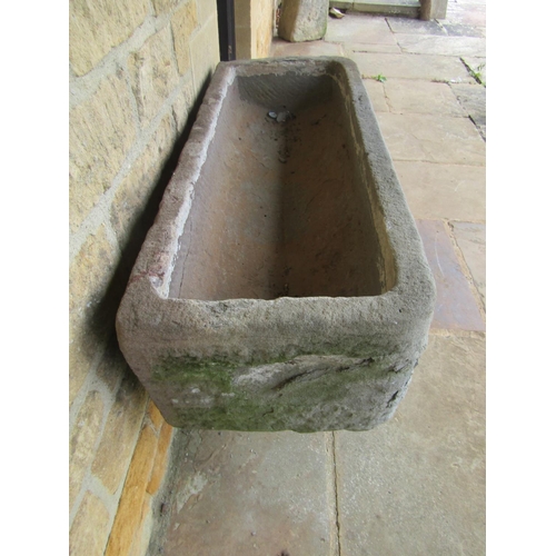 1051 - A roughly hewn weathered natural stone planter / trough of rectangular form raised on an associated ... 