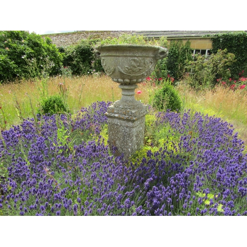 1068 - A weathered composition stone twin-handled urn shaped planter with moulded fruiting vine detail, rai... 