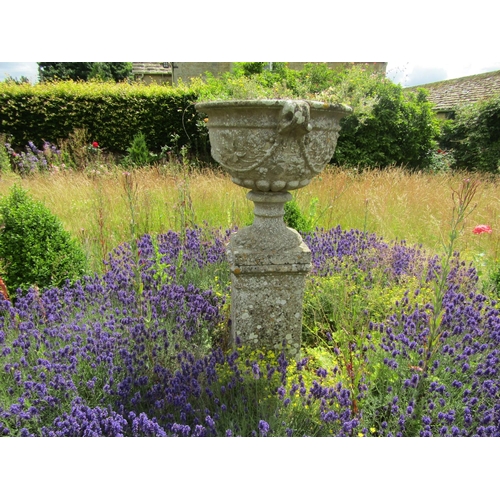 1068 - A weathered composition stone twin-handled urn shaped planter with moulded fruiting vine detail, rai... 