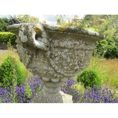 1068 - A weathered composition stone twin-handled urn shaped planter with moulded fruiting vine detail, rai... 