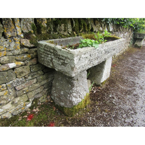 1071 - A weathered natural stone planter / trough of rectangular form, raised on a pair of associated stadd... 