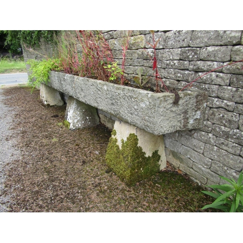 1073 - A very long weathered natural stone planter / trough of rectangular form, raised on a trio of associ... 