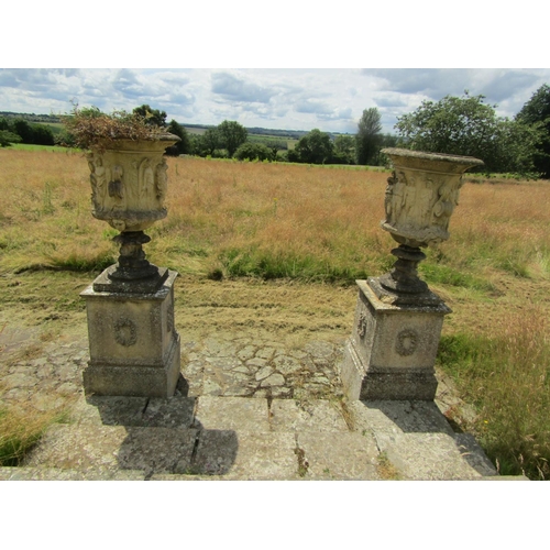 1097 - A monumental pair of 19th century weathered composition stone garden urns, raised on associated plin... 