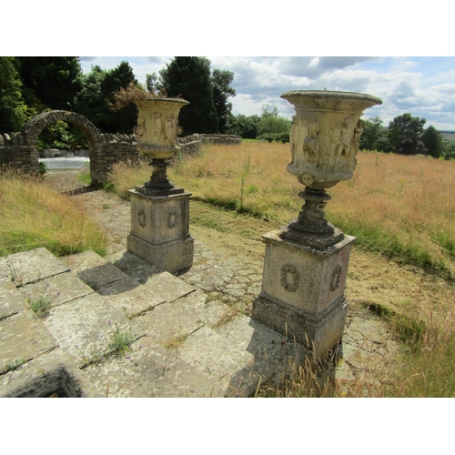 1097 - A monumental pair of 19th century weathered composition stone garden urns, raised on associated plin... 