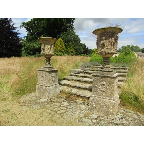A monumental pair of 19th century weathered composition stone garden urns, raised on associated plinth bases, the bowls of tapering form with high relief figural decoration flanked by scrolled handles beneath masks, over coiled serpent stems and stepped bases,  (with some cracking / losses and frost damage throughout) 235cm high (combined) the bases 66 x 66cm.

From the collection of a private North Cotswolds estate. Displayed in situ and sold from the rostrum in Wotton-under-Edge. Personal viewing ahead of sale on Monday 22nd July. Interested parties please enquire with the office for details of the property’s address. 

Purchases from this collection need to be removed by close of play of Friday 26th July or by alternative arrangements approved by the auctioneers.