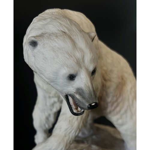 96 - A Franklin Mint hand painted porcelain figure of a polar bear on a rocky out crop, 26cm high