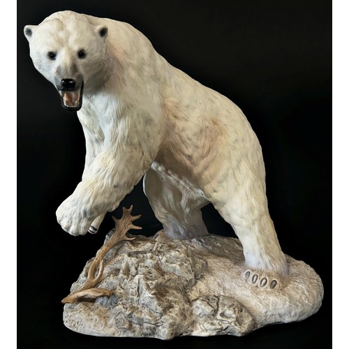 96 - A Franklin Mint hand painted porcelain figure of a polar bear on a rocky out crop, 26cm high