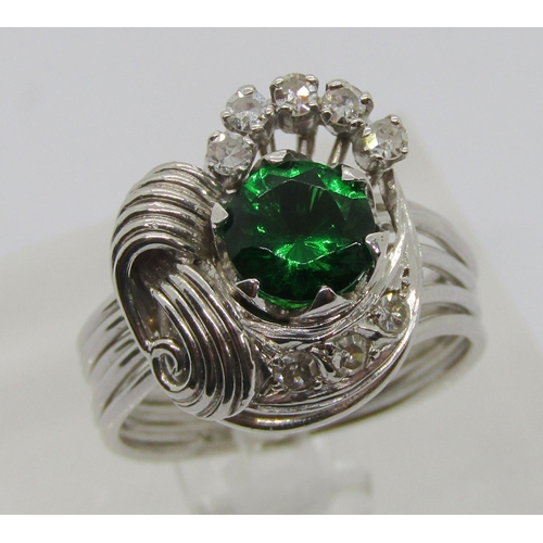 312 - Stylised white metal dress ring set with green paste and diamonds, size M, 7.7g