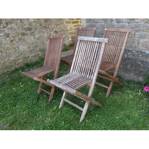 1024 - A set of four contemporary stained and weathered teak folding garden chairs with slender slatted sea... 