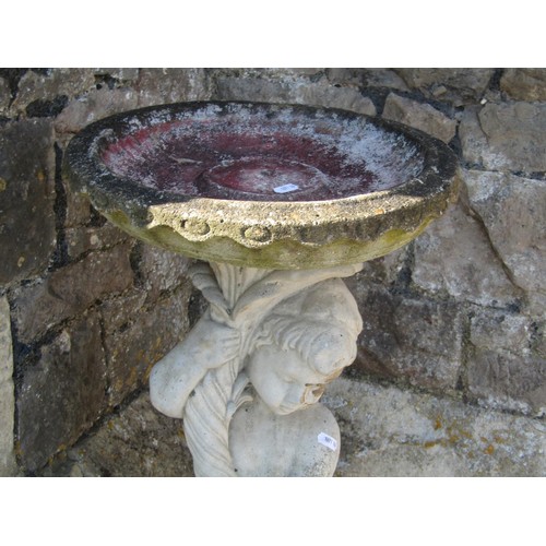 1015 - A two sectional weathered cast composition stone bird bath, the pedestal in the form of a standing c... 