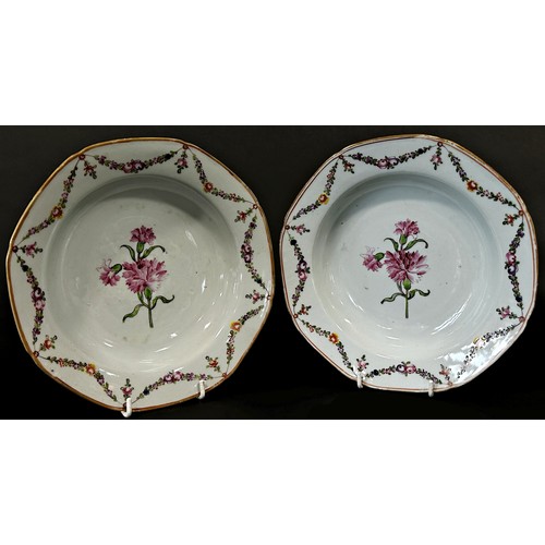 74 - Two 18th century Chinese export dishes hand painted with carnations within a floral swag border (2)