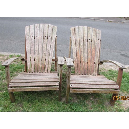 1016 - A pair of weathered heavy gauge hardwood fan back garden open armchairs, in the Art Deco style, with... 