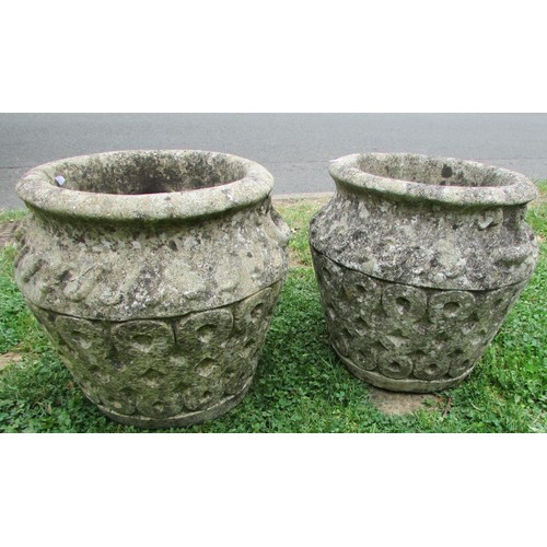 1020 - A pair of weathered cast composition stone garden urns with repeating relief detail and fixed ring h... 