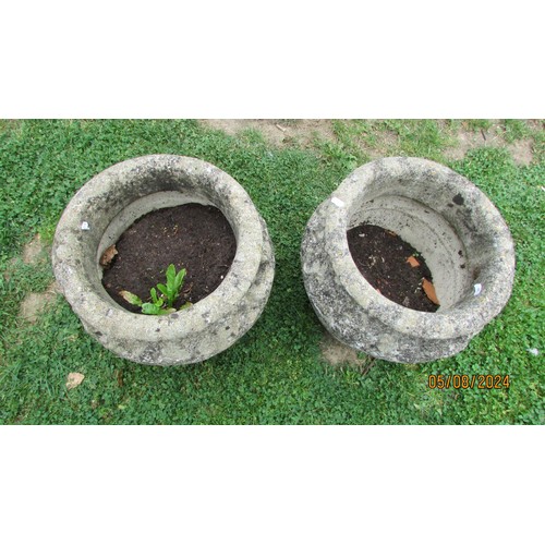 1020 - A pair of weathered cast composition stone garden urns with repeating relief detail and fixed ring h... 