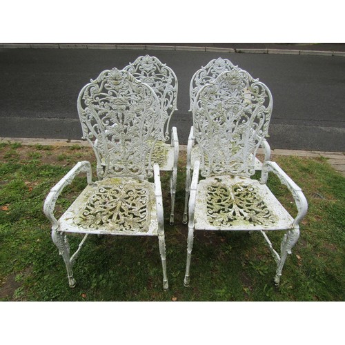 1068 - A set of four cream painted and weathered heavy gauge cast metal garden open armchairs with decorati... 