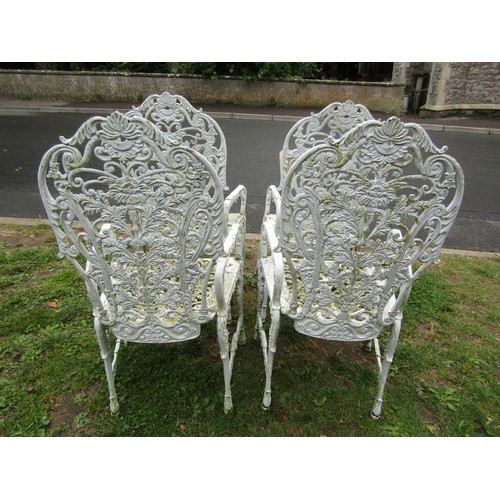 1068 - A set of four cream painted and weathered heavy gauge cast metal garden open armchairs with decorati... 