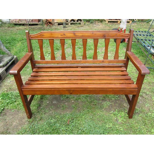 1079 - A contemporary stained softwood two seat garden bench with slatted seat and back, 124 cm wide