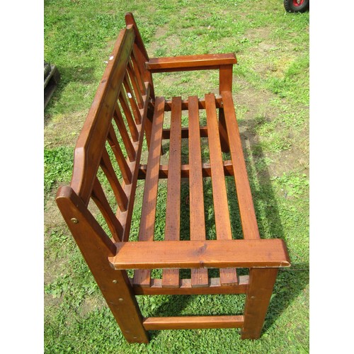 1079 - A contemporary stained softwood two seat garden bench with slatted seat and back, 124 cm wide