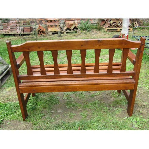 1079 - A contemporary stained softwood two seat garden bench with slatted seat and back, 124 cm wide