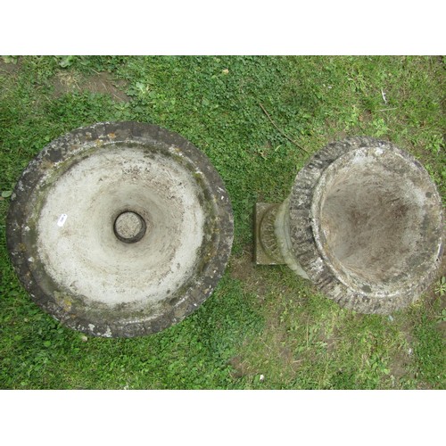 1066 - Two similar weathered composition stone garden urns with flared rims and lobbed bodies raised on loo... 