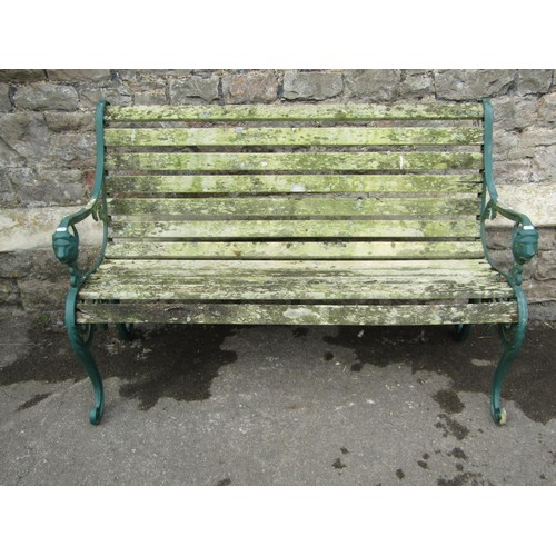 1078 - A two seat garden bench with weathered wooden slatted seat and combined back raised on decorative pa... 