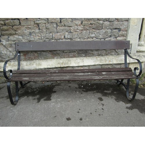 1071 - A vintage garden bench with stained wooden slatted seat and simple rail back raised on sprung steel ... 