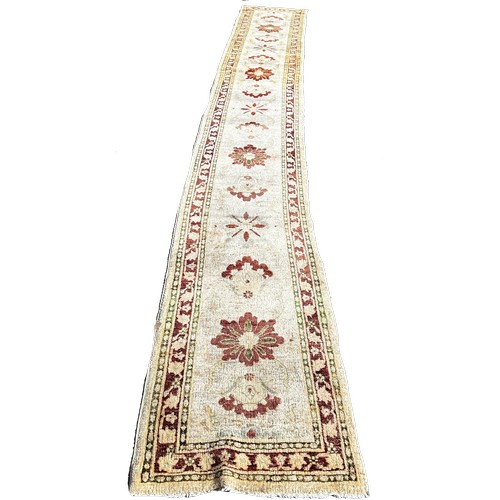 1786 - An Afghan runner, sixteen floral medallions on an ivory field, 610cm x 70cm