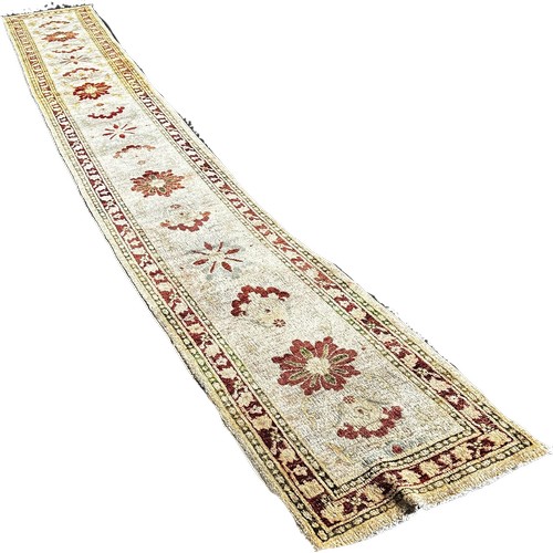 1786 - An Afghan runner, sixteen floral medallions on an ivory field, 610cm x 70cm