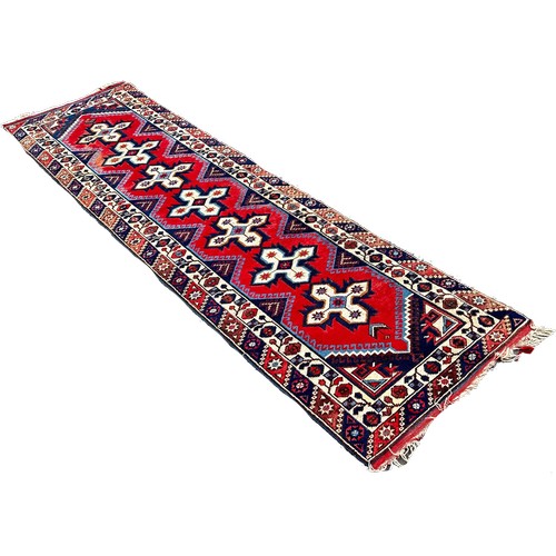 1761 - A Kazak type runner with seven star medallions on a red ground, 300cm x 80 cm