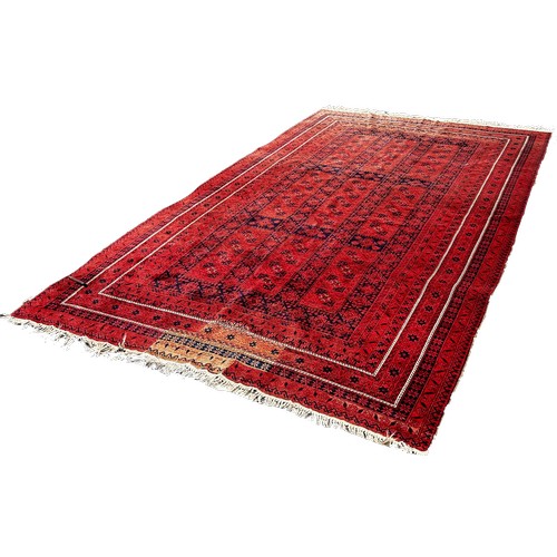 1770 - A Middle Eastern Carpet with an all over geometric pattern on a red ground, 320cm x 205cm approximat... 