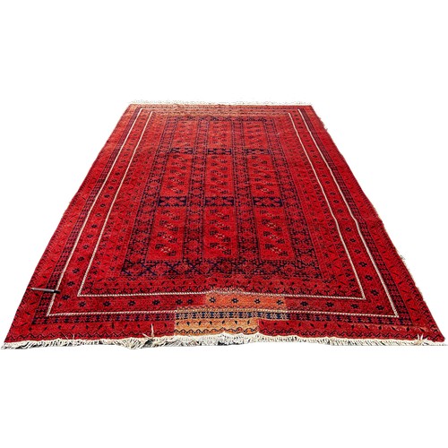 1770 - A Middle Eastern Carpet with an all over geometric pattern on a red ground, 320cm x 205cm approximat... 