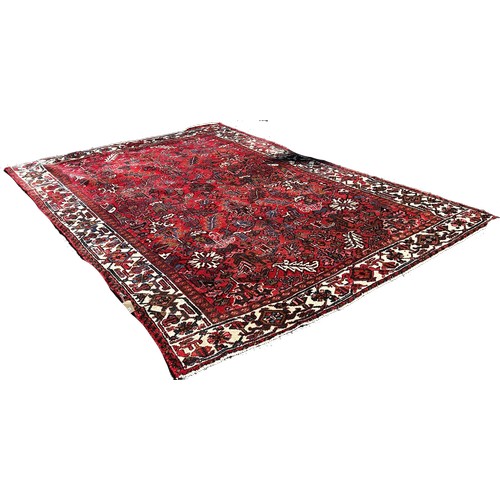 1782 - A Heriz carpet, with an all over stylised floral design on a red ground and floral border, 330cm x 2... 