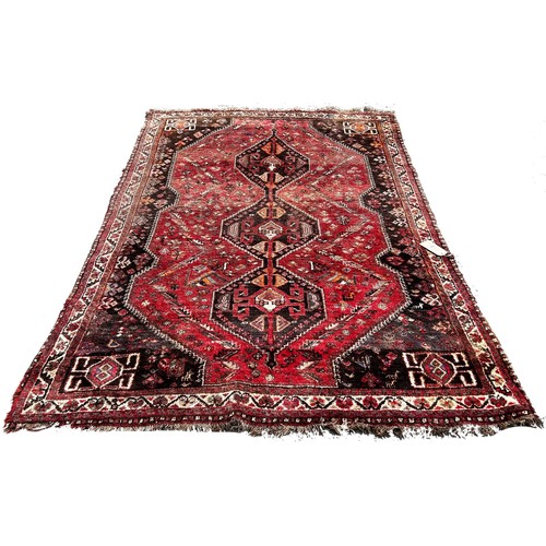 1793 - An old worn and faded Persian rug with three interlocking medallions, 245cm x 164cm approximately