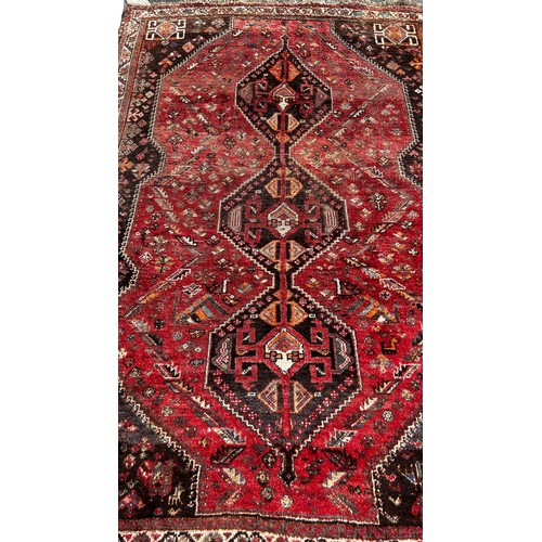 1793 - An old worn and faded Persian rug with three interlocking medallions, 245cm x 164cm approximately