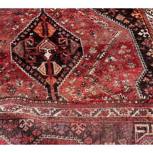 1793 - An old worn and faded Persian rug with three interlocking medallions, 245cm x 164cm approximately