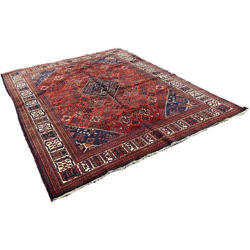 1772 - A Persian carpet with central blue diamond medallion with an all over floral design on a red and blu... 