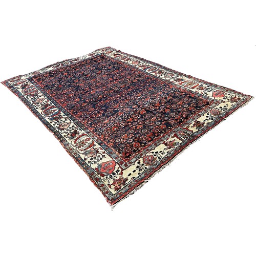 1778 - An antique Persian carpet, with an all over floral pattern on a predominantly blue ground and floral... 