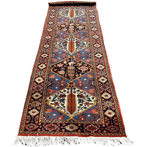 1785 - A Persian runner with alternating diamond medallions and floral borders, 290cm x 85cm approximately