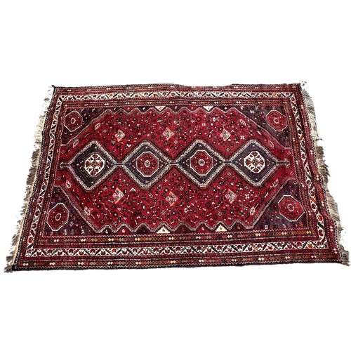 1758 - An antique Qashqai carpet with four linked diamond medallions on a predominantly red ground, 280cm x... 