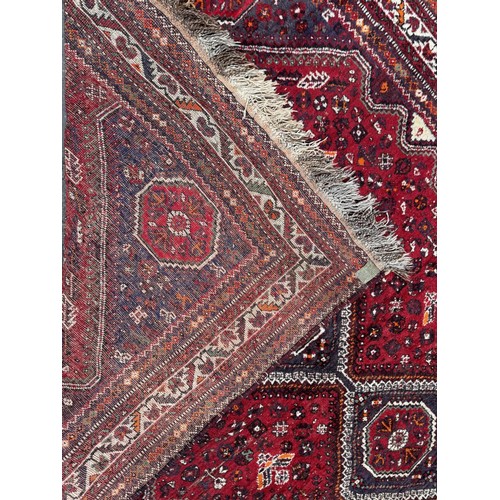 1758 - An antique Qashqai carpet with four linked diamond medallions on a predominantly red ground, 280cm x... 