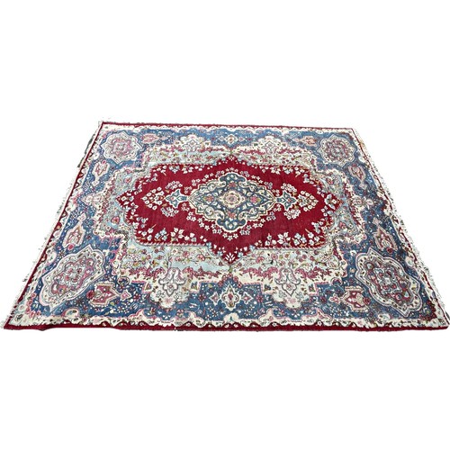 1763 - An old  Kirman carpet with a floral elongated medallion on a crimson field and blue floral borders 3... 